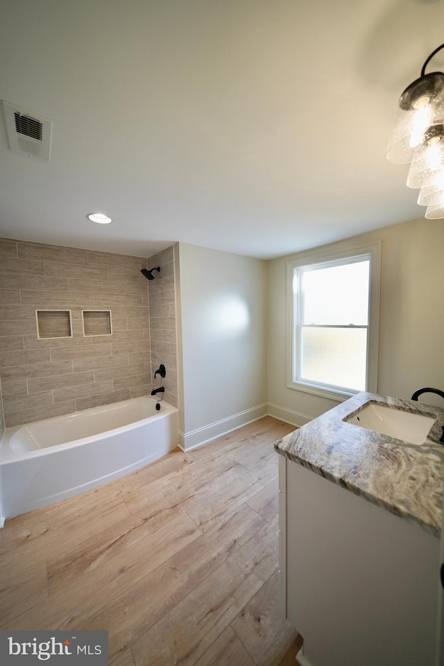 bathroom featuring hardwood / wood-style floors, vanity, and tiled shower / bath combo