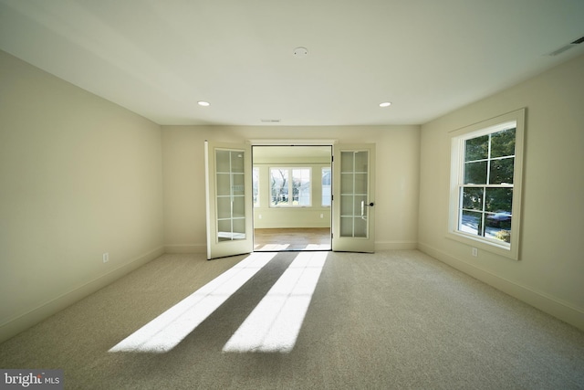 carpeted spare room featuring french doors