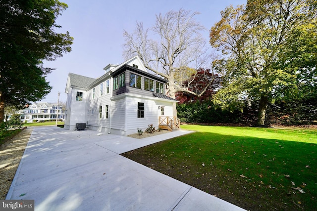 view of side of property with central AC and a lawn