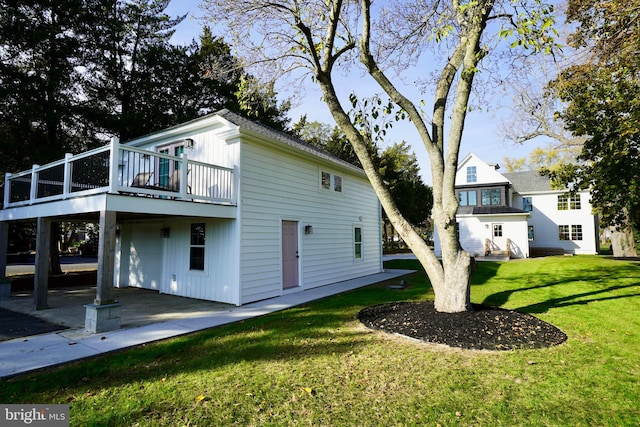 rear view of house featuring a garage, a wooden deck, and a lawn