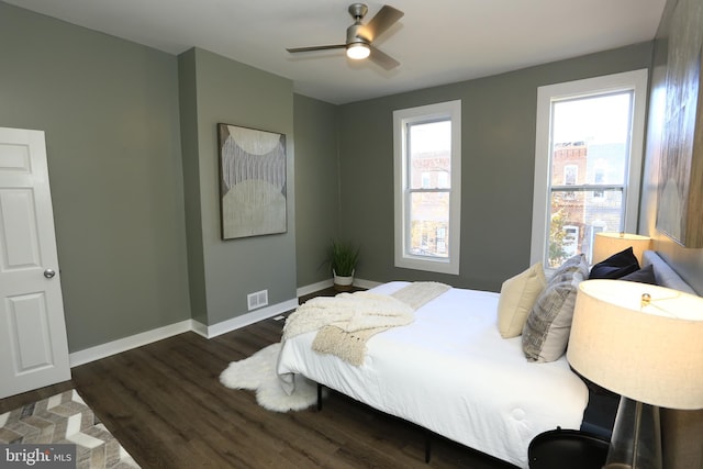 bedroom with ceiling fan, dark wood-type flooring, and multiple windows