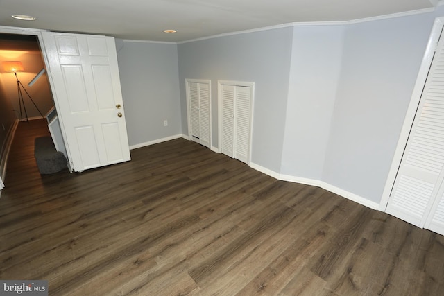 unfurnished bedroom with multiple closets, crown molding, and dark hardwood / wood-style floors