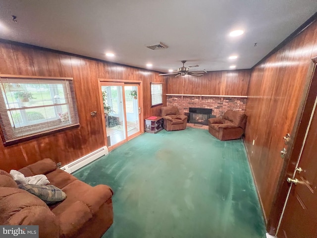 living room with carpet, ceiling fan, wooden walls, a baseboard radiator, and a fireplace