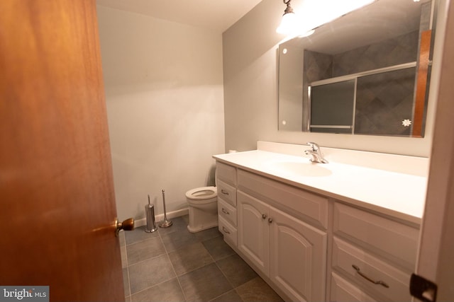 bathroom featuring tile patterned flooring, vanity, toilet, and a shower with door