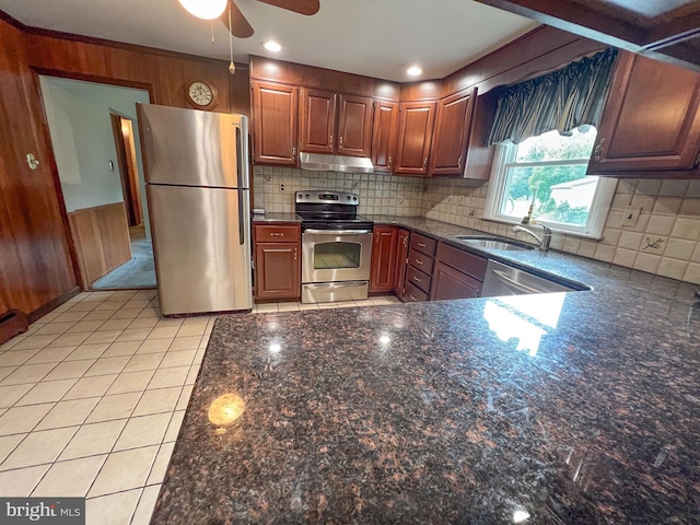 kitchen with ceiling fan, wood walls, sink, and stainless steel appliances