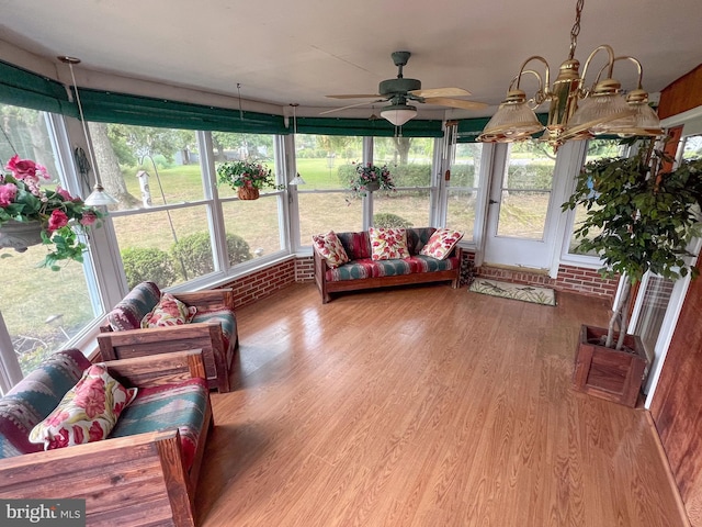 sunroom featuring ceiling fan with notable chandelier