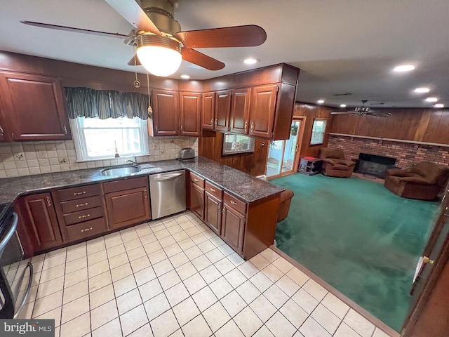 kitchen featuring sink, stainless steel appliances, a brick fireplace, wooden walls, and decorative backsplash