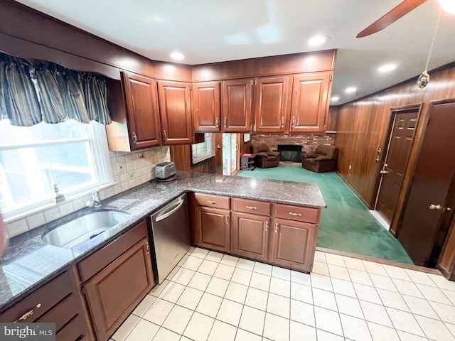 kitchen featuring dishwasher, sink, backsplash, kitchen peninsula, and wooden walls