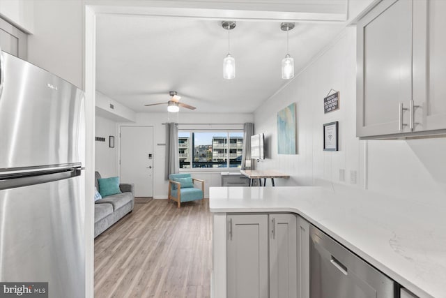 kitchen with kitchen peninsula, appliances with stainless steel finishes, ceiling fan, decorative light fixtures, and light hardwood / wood-style floors