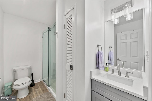 bathroom with walk in shower, hardwood / wood-style floors, vanity, and toilet