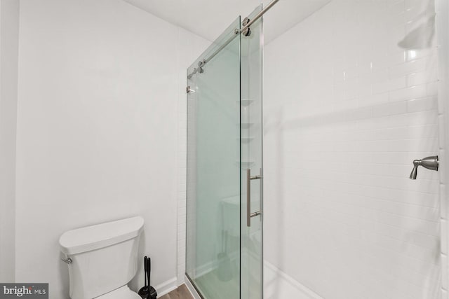 bathroom with a shower with shower door and toilet