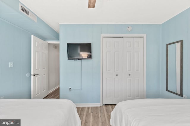 bedroom with ceiling fan, wood-type flooring, crown molding, and a closet