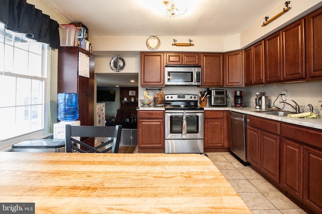 kitchen featuring light tile patterned flooring, stainless steel appliances, wood counters, and sink