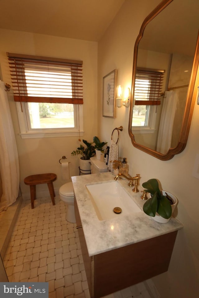 bathroom featuring tile patterned floors, toilet, vanity, and walk in shower