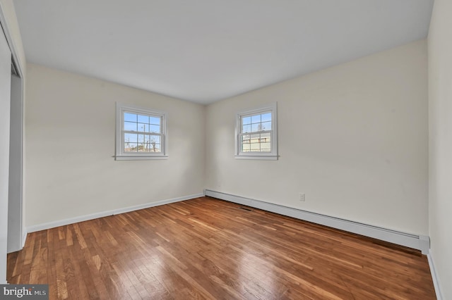 spare room with wood-type flooring and a baseboard heating unit