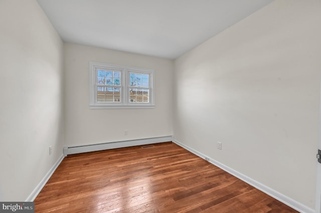 unfurnished room with baseboard heating and hardwood / wood-style flooring