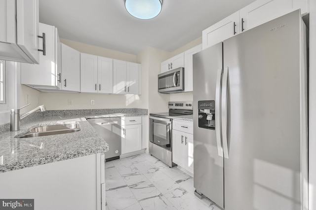 kitchen featuring light stone counters, stainless steel appliances, white cabinetry, and sink