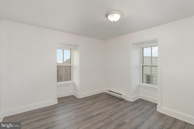 unfurnished room with a wealth of natural light, dark hardwood / wood-style flooring, and a baseboard heating unit