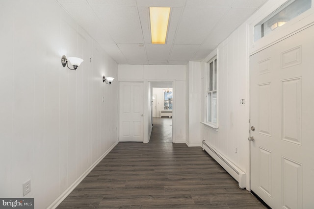 corridor featuring a healthy amount of sunlight, dark hardwood / wood-style flooring, wooden walls, and a baseboard heating unit