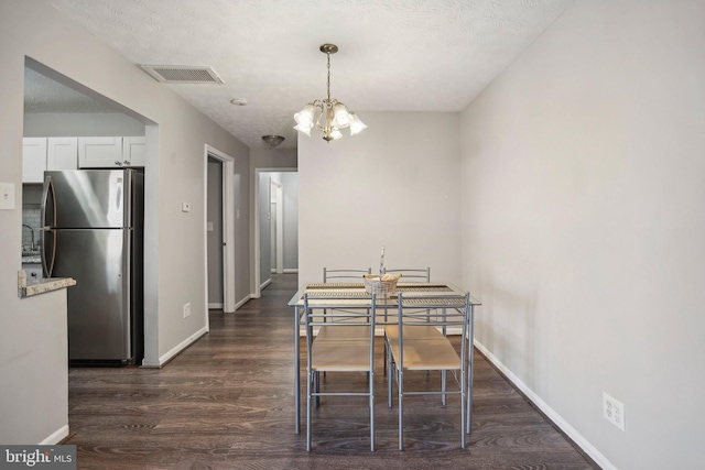 dining area featuring a chandelier, sink, dark wood-type flooring, and a textured ceiling