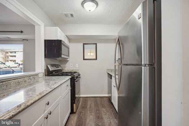 kitchen featuring light stone countertops, appliances with stainless steel finishes, a textured ceiling, white cabinets, and dark hardwood / wood-style floors