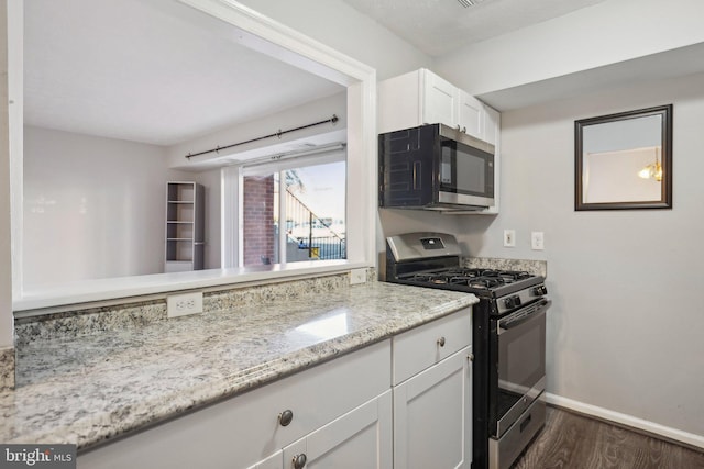 kitchen featuring light stone countertops, white cabinets, dark wood-type flooring, and appliances with stainless steel finishes