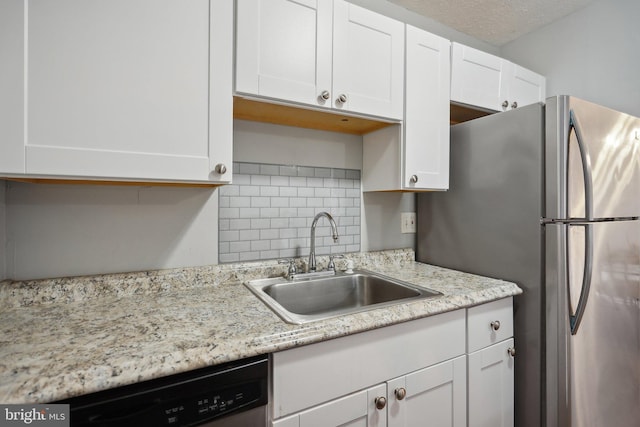 kitchen featuring backsplash, a textured ceiling, stainless steel appliances, sink, and white cabinets