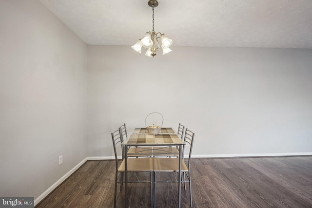 dining area featuring a chandelier, a textured ceiling, and dark wood-type flooring