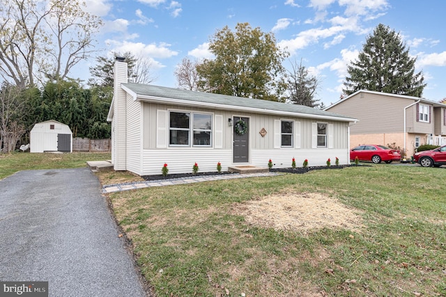 view of front of home with a front yard and a storage shed