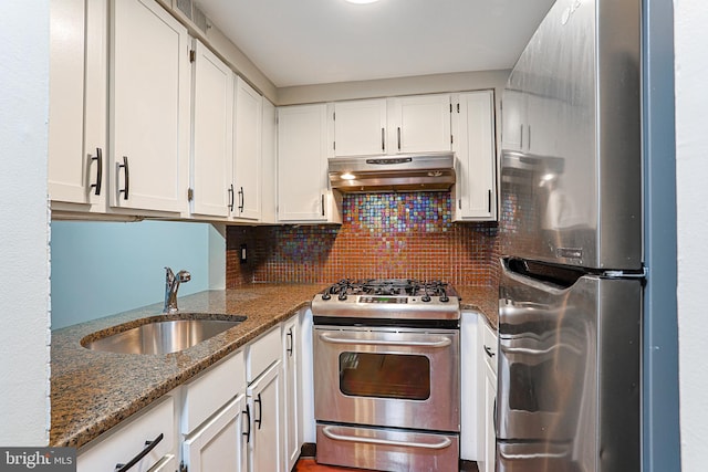 kitchen with stainless steel appliances, white cabinetry, dark stone counters, and sink