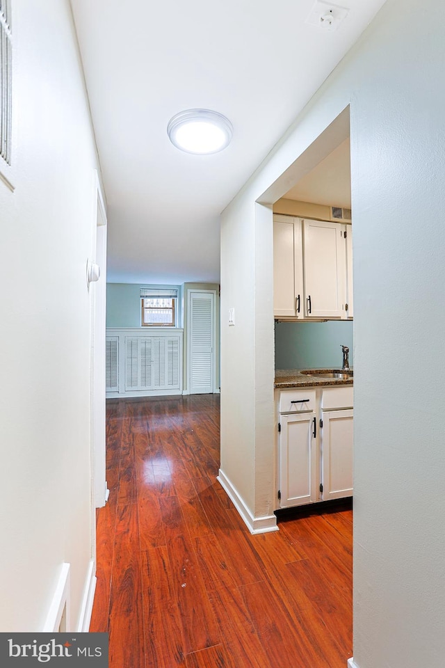 corridor featuring dark wood-type flooring and sink