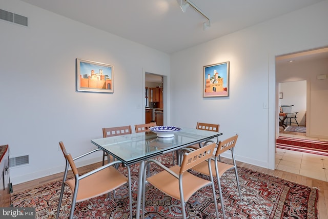 dining area featuring rail lighting and light hardwood / wood-style flooring