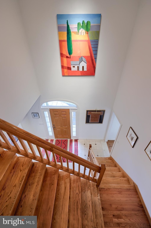 stairway with hardwood / wood-style flooring and a towering ceiling