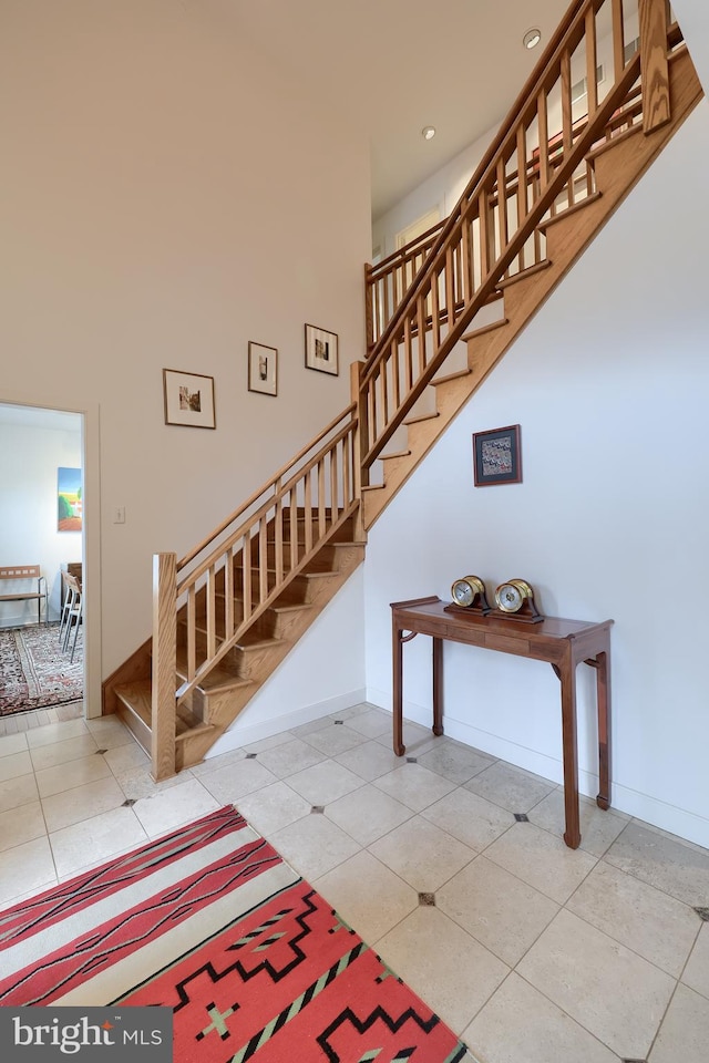 stairway with tile patterned flooring and a towering ceiling