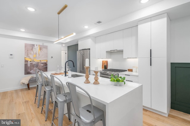 kitchen with white cabinets, a center island with sink, stainless steel appliances, and sink