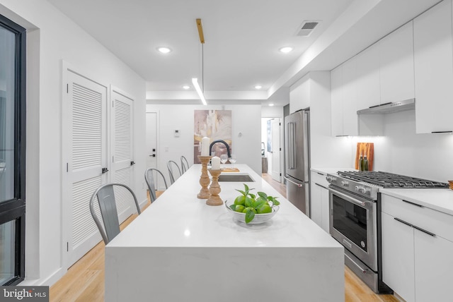 kitchen featuring sink, a kitchen island, premium appliances, light hardwood / wood-style flooring, and white cabinets