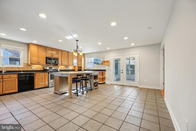 kitchen with a breakfast bar, light tile patterned floors, plenty of natural light, and black appliances