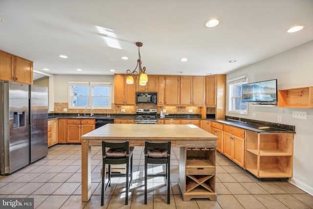 kitchen with black appliances, decorative light fixtures, a center island, and light tile patterned flooring