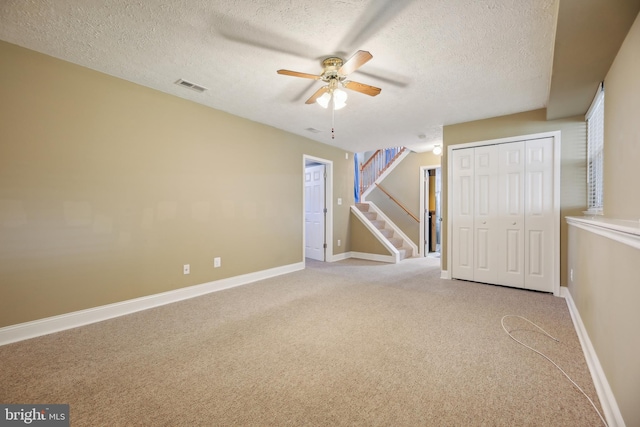 carpeted empty room with ceiling fan and a textured ceiling