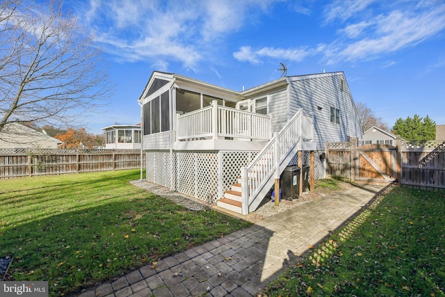 rear view of house with a sunroom, a deck, and a yard