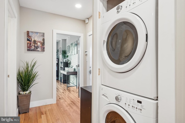 laundry area with stacked washer and dryer and light hardwood / wood-style flooring