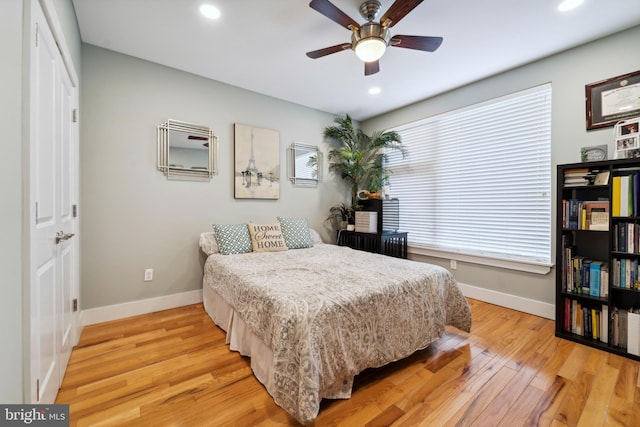 bedroom featuring ceiling fan, light hardwood / wood-style flooring, and multiple windows