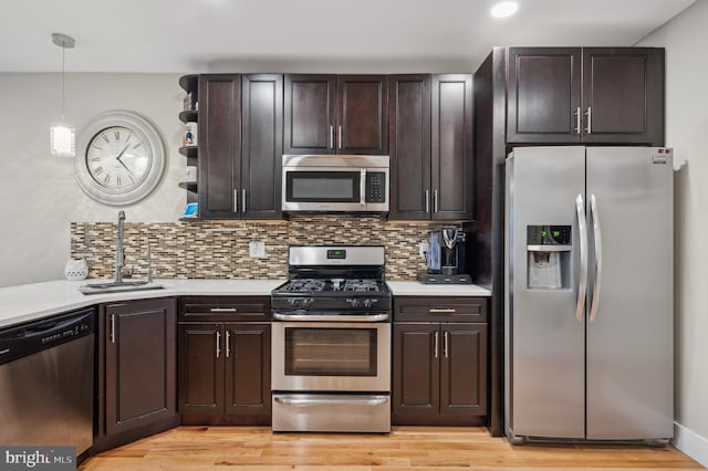 kitchen with appliances with stainless steel finishes, light hardwood / wood-style floors, dark brown cabinets, and sink