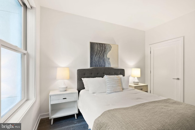 bedroom with dark hardwood / wood-style floors and multiple windows