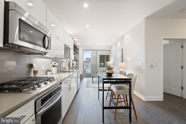 kitchen featuring dark hardwood / wood-style flooring, white cabinetry, sink, and stainless steel appliances