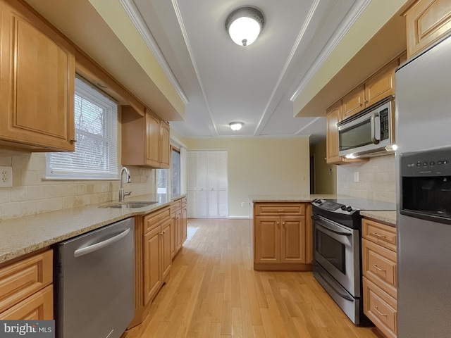 kitchen with appliances with stainless steel finishes, light hardwood / wood-style floors, ornamental molding, and sink