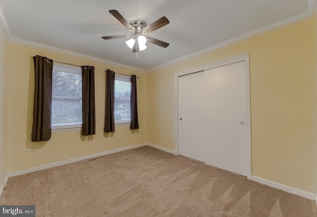 unfurnished bedroom featuring a closet, ceiling fan, ornamental molding, and light colored carpet