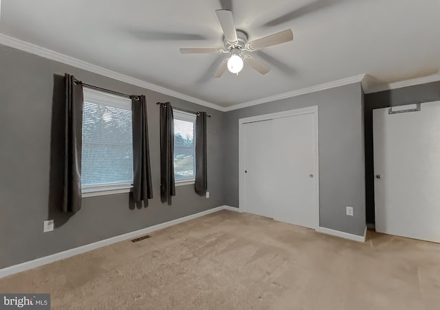 unfurnished bedroom featuring ceiling fan, light colored carpet, ornamental molding, and a closet