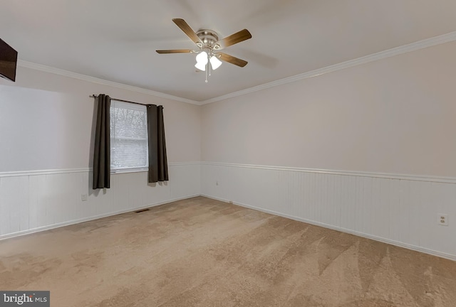 empty room with ceiling fan, light colored carpet, and ornamental molding