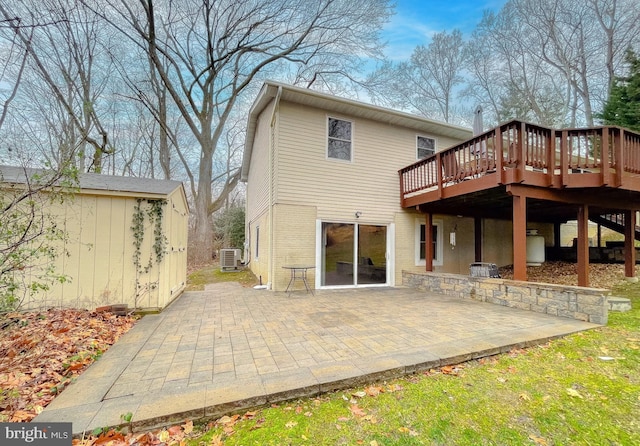 rear view of house with a wooden deck and a patio